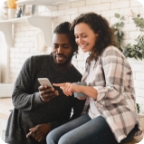 Couple look at cellphone together, woman points at the screen.